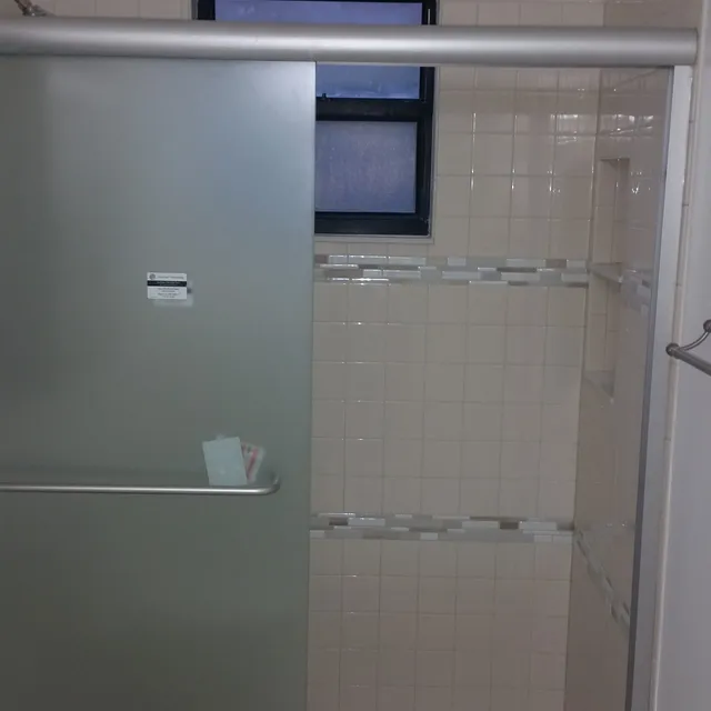 Glass shower door with white tile and accent stripe
