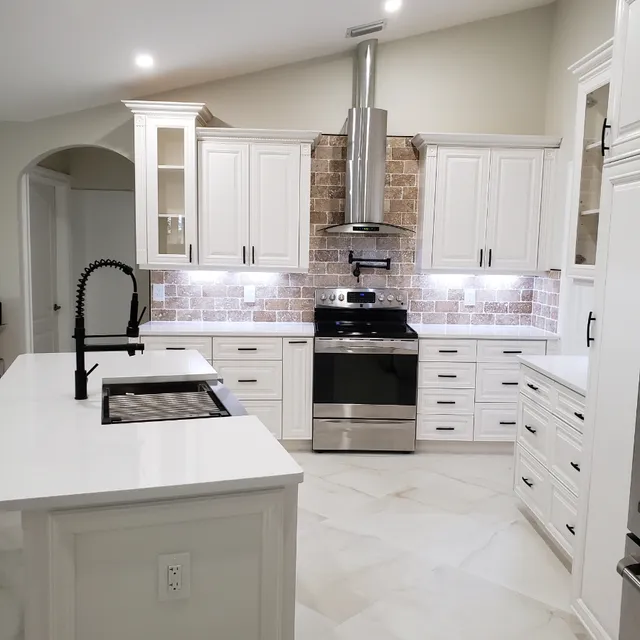 Remodeled white kitchen with quartz island, stainless range hood and brick backsplash