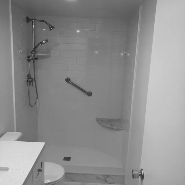 Finished white tile shower with grab bar and corner shelf