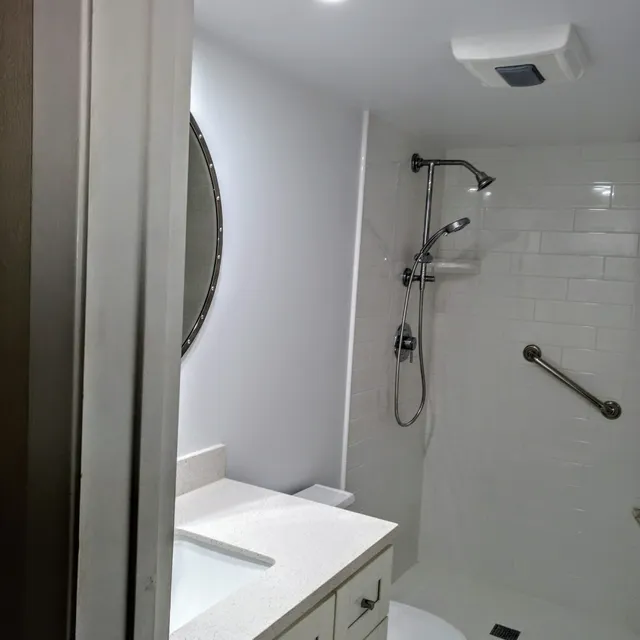Bathroom with round mirror and tiled shower