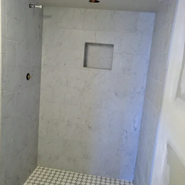 Marble-look tile shower with recessed niche