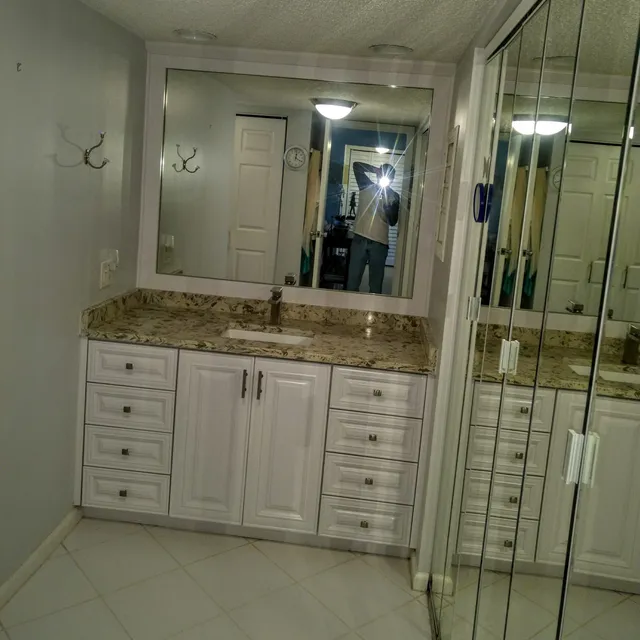 Bathroom vanity with granite counter next to a glass shower