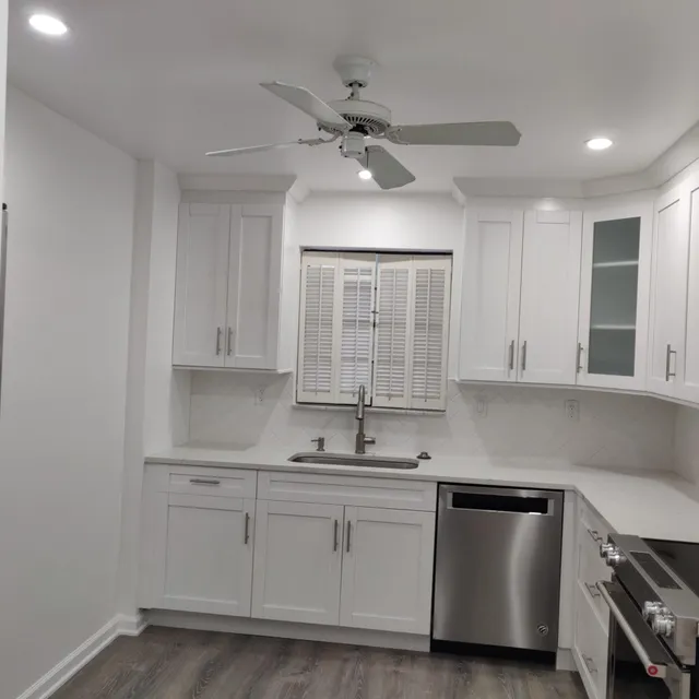 White kitchen with sink under a shuttered window and new flooring