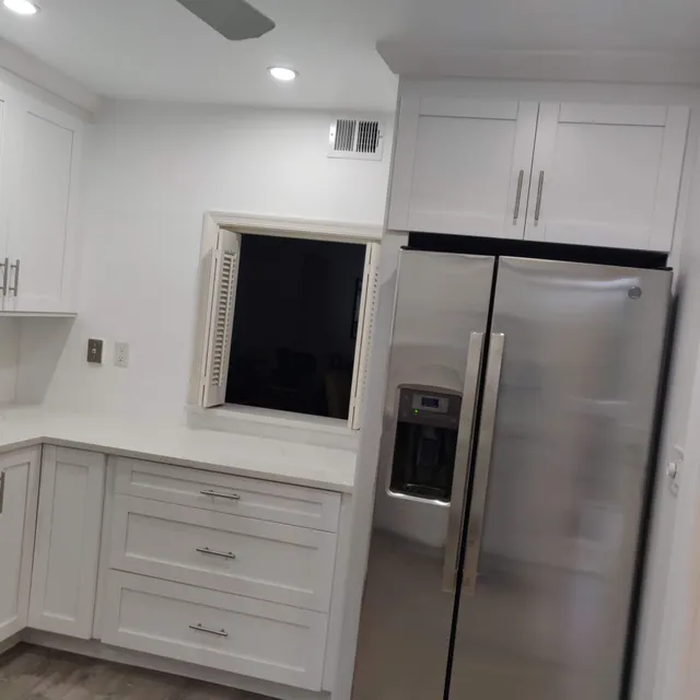 White cabinetry built around a stainless refrigerator