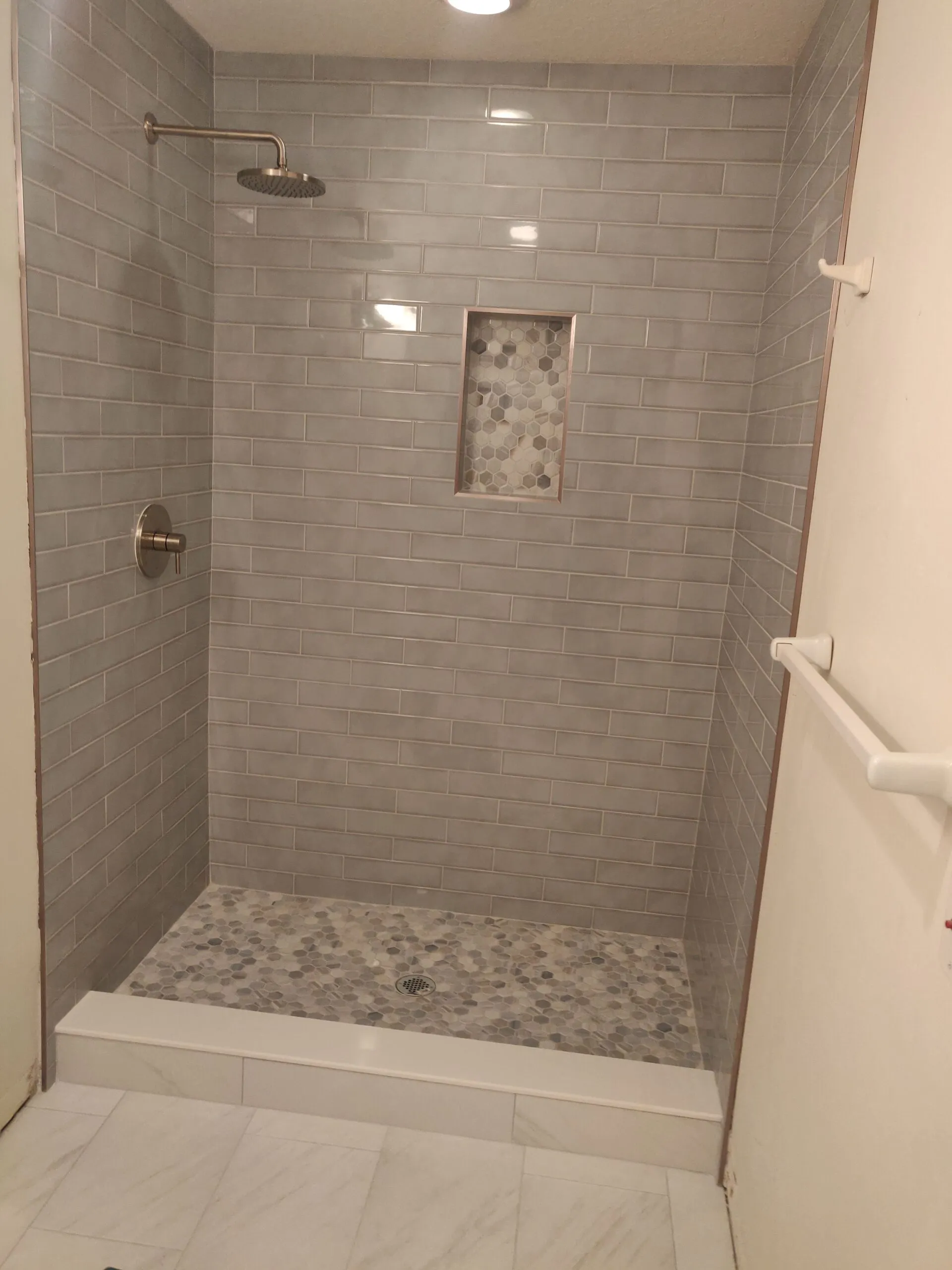 Gray tile shower with pebble niche and pebble floor