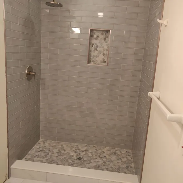 Gray tile shower with pebble niche and pebble floor