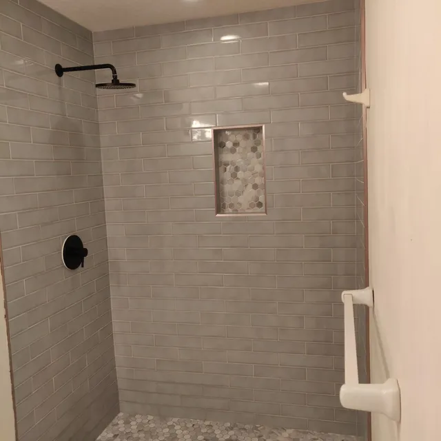 Gray tile shower with matte black fixtures and grab bar