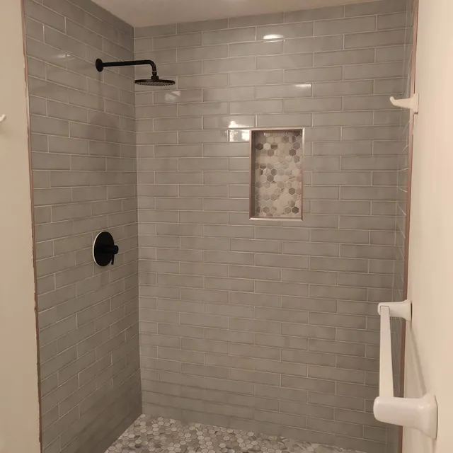 Gray tile shower with rain shower head and pebble niche