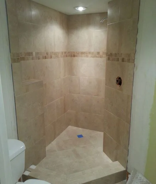 Shower almost complete: beige tile walls with a decorative accent band